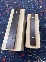 Two contra bass chime bars placed on a star-patterned carpet, showing both top and side angles of the dark wooden bars mounted on light wooden resonator boxes.