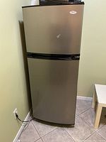 Exterior front view of stainless steel refrigerator with top-mounted freezer
