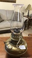 Image showing antique brass centre draft oil lamp with clear glass chimney on a wooden surface in a living room setting