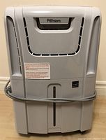 Front view of the white Danby Premiere dehumidifier with attached power cord wrapped around base.