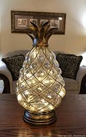 Glass and bronze pineapple shaped light illuminated to show bubble glass texture and bronze frame