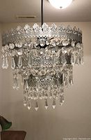 Front view showing the three-tier swag ceiling lamp with silver metal and hanging glass pendants.