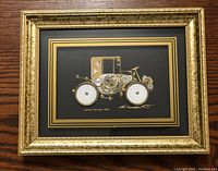 Framed collage picture of the 1900 Lohner Porsche made entirely from watch parts, displayed on a wooden surface.