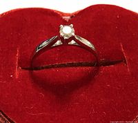 Ring shown from side angle in red heart-shaped box