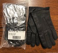 One pair of men's black lined leather dress gloves still in original plastic package, with label showing size and color details.