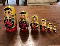 All six Russian nesting dolls arranged in a row from largest to smallest on a wooden surface.