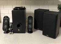 Logitech computer sound system with subwoofer and two satellite speakers next to KLH bookshelf speakers.