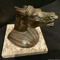 Close-up of bronze horse head sculpture showing patina and base texture.