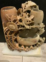 Front detailed view of the intricately carved soapstone vase illustrating floral motifs and openwork craftsmanship on the stone, onyx base shown underneath.