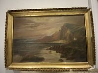 Full view of the antique oil on board landscape painting in original decorative gold-toned frame showing coastal cliffs, boat, and moody sky.