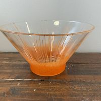 Front angle of large vintage glass sunburst bowl with orange base and clear top showing sunburst pattern