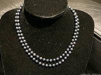 Necklace draped on black display bust showing double-strand styling