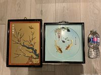 Pair of vintage Asian carved stone pictures in original frames shown side by side with water bottle for scale.