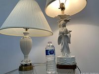 Photo showing two vintage blanc-de-chine porcelain lamps with ivory fabric shades and water bottle for size comparison