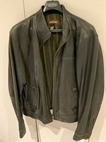 Full front view of Danier black leather jacket on hanger showing vertical striped lining and collar