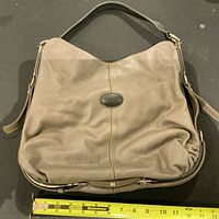 Photo of the vintage TODS leather hobo handbag from front, showing taupe leather material, shoulder strap and TODS logo plaque.