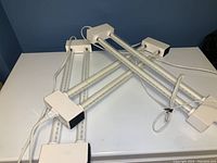 Three white LED light bars arranged on a white surface, with cables showing for interconnection and power.