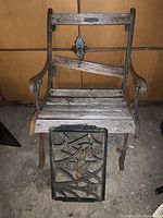 Front view of the bench showing the wooden slats seat and backrest frame with some missing wood pieces and decorative metal panel resting on the floor