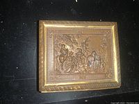 Top view of the rectangular brass trinket box showing detailed engraved scene with horses and people.