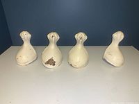 Four clawfoot bathtub feet, white paint with chips and wear, shown together from the front.