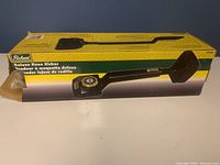 Photo of the original yellow and green box with image of the Deluxe Knee Kicker on the front, box edges worn and damaged.