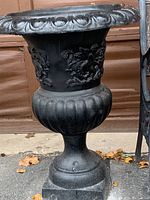 Full view of the large black urn showing the decorative angel motif and overall design