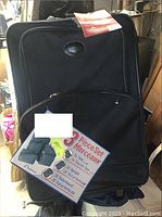 Front view of largest black suitcase with tag showing 3-piece set details and measurements.