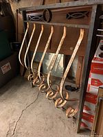 View of vintage cast iron fence with seven curled vertical bars, showing rust and wear.