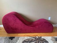 Side view of the wavy red exercise couch showing its curved design and plush fabric.