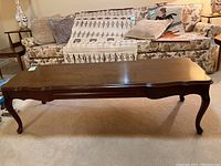 Front and side view of wood coffee table with curved legs and worn finish.