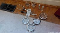 Full view of lot items on floor showing all items including meat fork, cutting utensil, candle holders, salt and pepper shakers, and coasters.