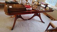 Wood table with metal claw foot toe caps shown from side angle with window light.