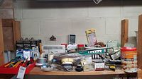 A wide view of the workbench showing various hand tools, tapes, screws, a spirit level, and a power cost monitor.