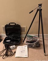 Full black tripod standing upright, lighting cables and power cords laid out
