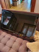 Front view of Samsung 32" flat screen TV on a cushioned surface showing the screen and frame.