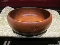 Front view of the brown wooden bowl showing the inside and the carved wheat pattern on the outside.