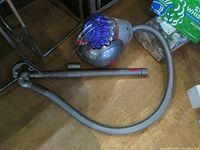 Full view of Dyson vacuum with hose and 10" beater bar head lying on floor