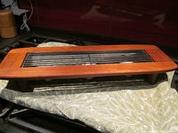 Top and front angle view of teak wooden warming tray featuring removable black metal grate, showing length and width proportions and base with four legs.