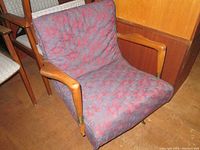 Front angle view showing armrests, seat, patterned upholstery and wooden legs with metal tips.