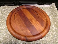 Top-down view of the round teak serving tray showing the polished wood grain and the recessed inner area with varying shades of teak wood.