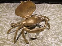 View of the brass crab ashtray with hinged top open exposing inner liner