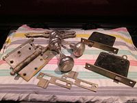 Complete set of two Yale door lock sets with knobs, faceplates, strike plates, keys and four metal door hinges arranged on fabric.