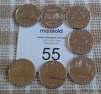 Top view of the seven Canadian nickel dollar coins arranged on a MaxSold auction paper. Dates visible include 1972, 1975, 1976, 1980, 1983, 1985, and 1974.