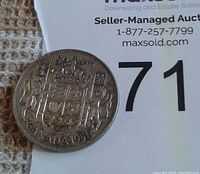 Photo showing the reverse side of the 1951 Canada silver half-dollar coin featuring the crowned Canadian coat of arms and the year 1951.