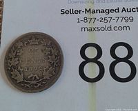 Reverse side of the 1892 Canadian silver 25 cent coin showing denomination, year and maple leaf wreath design.