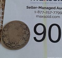 Reverse side of 1913 Canada silver quarter coin showing denomination 25 cents surrounded by maple leaf wreath.