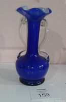 Front view of the handblown blue glass vase showing the tall neck and clear glass handles.