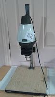 Front view of LPL enlarger with blue/green top mounted on wooden base with cord visible