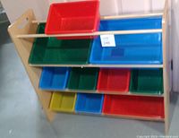 Wooden organizer bin rack with 10 colorful plastic bins placed on three horizontal wooden rods inside the rack. Bins vary in size, colors include red, blue, green, and yellow.