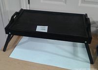 Black wooden tray table with legs extended and tray set flat